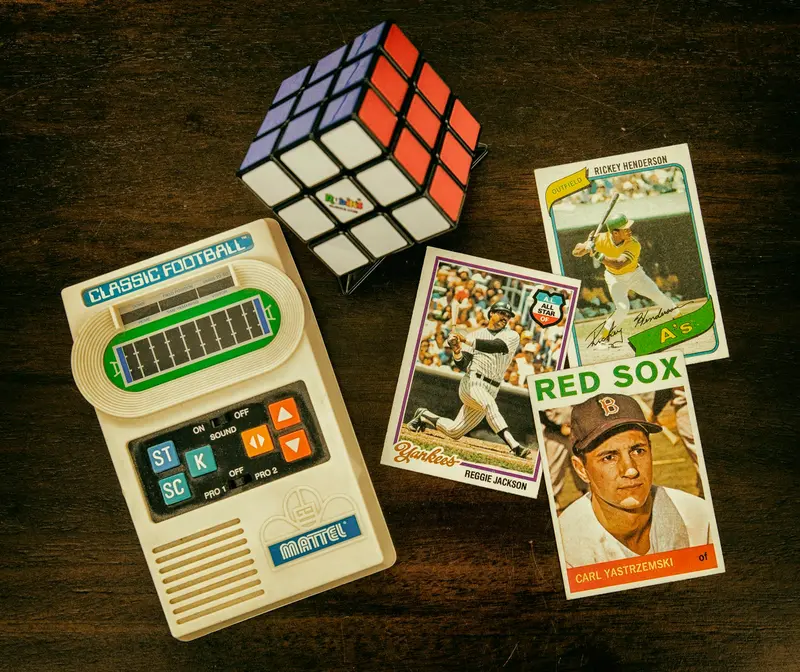 Baseball cards on a collector's desk next to a retro handheld game