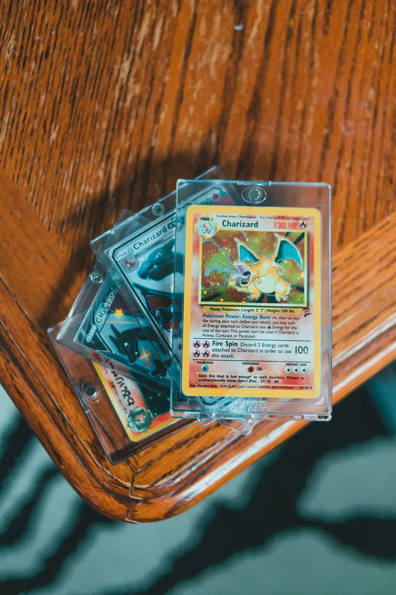 Trading cards in rigid holders resting on the edge of a wooden table